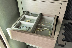 A three drawer safe box with a light gray wood-grain finish, featuring one drawer pulled open to show jewelry inside storage compartments.
